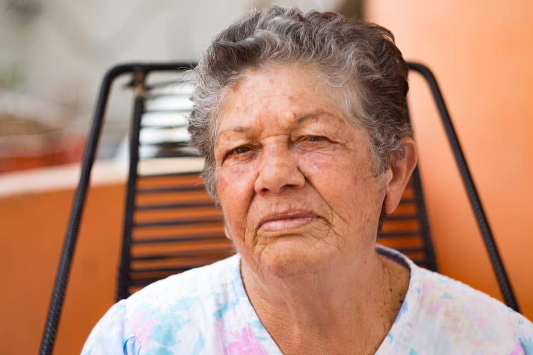 Idosa brasileira sentada, expressão séria